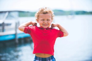 5 year old boy flexing his muscles by the water
