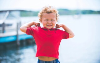 5 year old boy flexing his muscles by the water